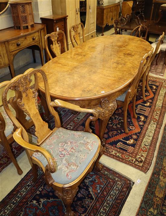 A Queen Anne style burr walnut extending dining table and a set of six matching chairs with foliate carved framed and cabriole legs wit